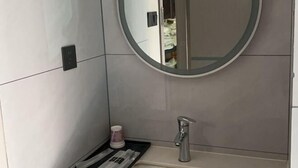 A bathroom with a round mirror, a sink, and a towel rack.