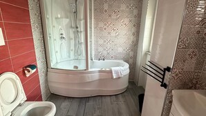 Un bagno con vasca idromassaggio, due servizi igienici e una doccia.