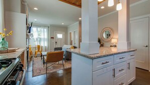 A modern kitchen with white cabinetry, granite countertops, and pendant lighting. - Charming Home | Near DT, Pet Friendly! (Nashville)