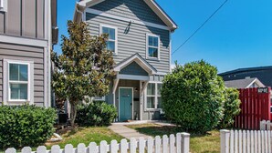 A two-story house with a front porch, a green door, and a red fence. - Charming Home | Near DT, Pet Friendly! (Nashville)