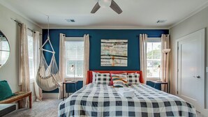 A bedroom with a bed, a hanging chair, a bench, and a window with curtains. - Charming Home | Near DT, Pet Friendly! (Nashville)