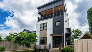Une maison moderne à deux étages, dotée d’un toit plat, de grandes fenêtres et d’une terrasse en bois.