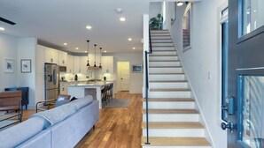 Une cuisine moderne avec des meubles blancs, un îlot central et des luminaires suspendus.