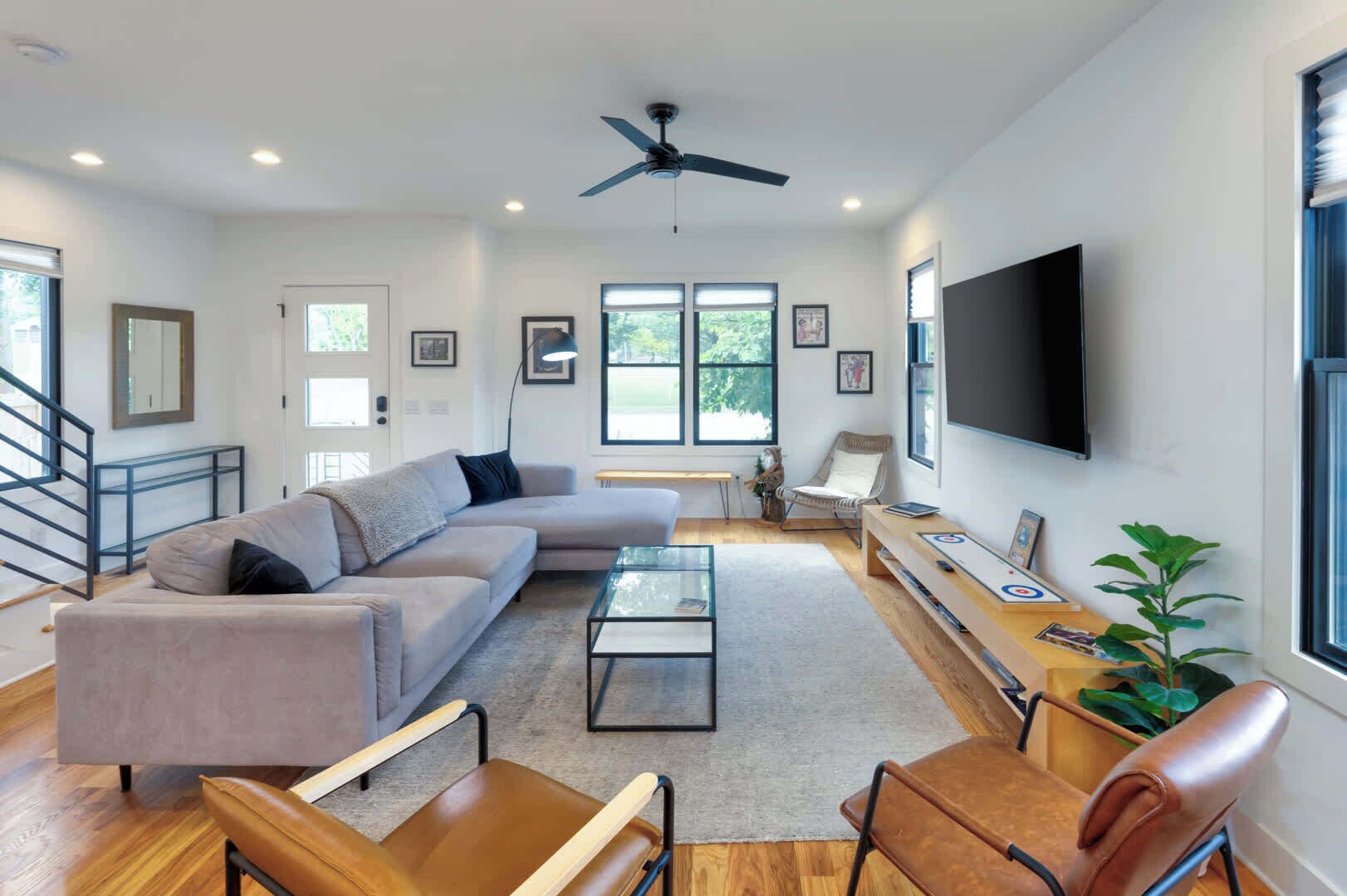 A modern living room with a sectional sofa, a coffee table, and a TV mounted on the wall.