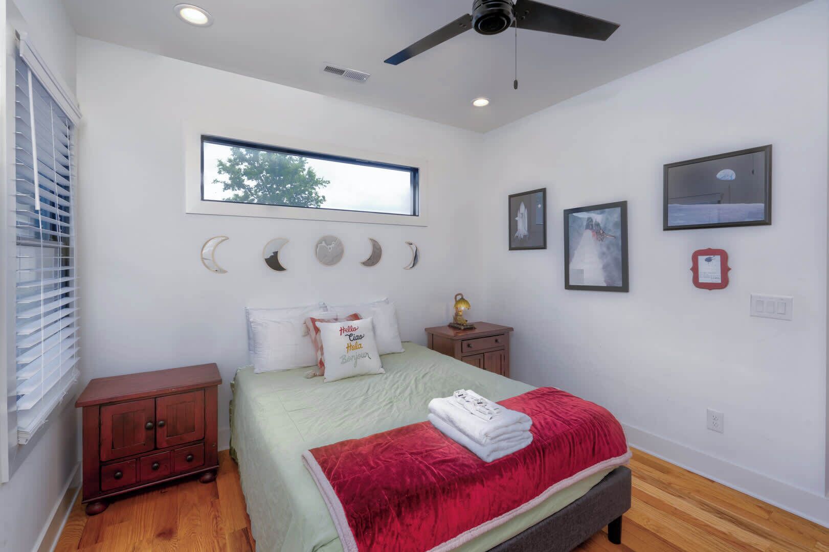 Un dormitorio con cama, mesita de noche, ventana y adornos en la pared.