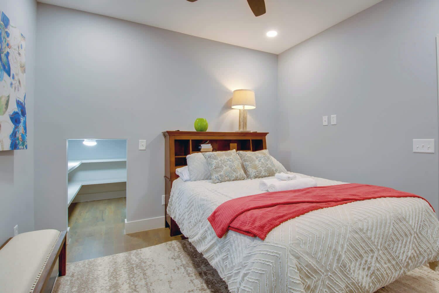 Une chambre à coucher avec un lit, une table de chevet, une lampe et un tableau au mur.