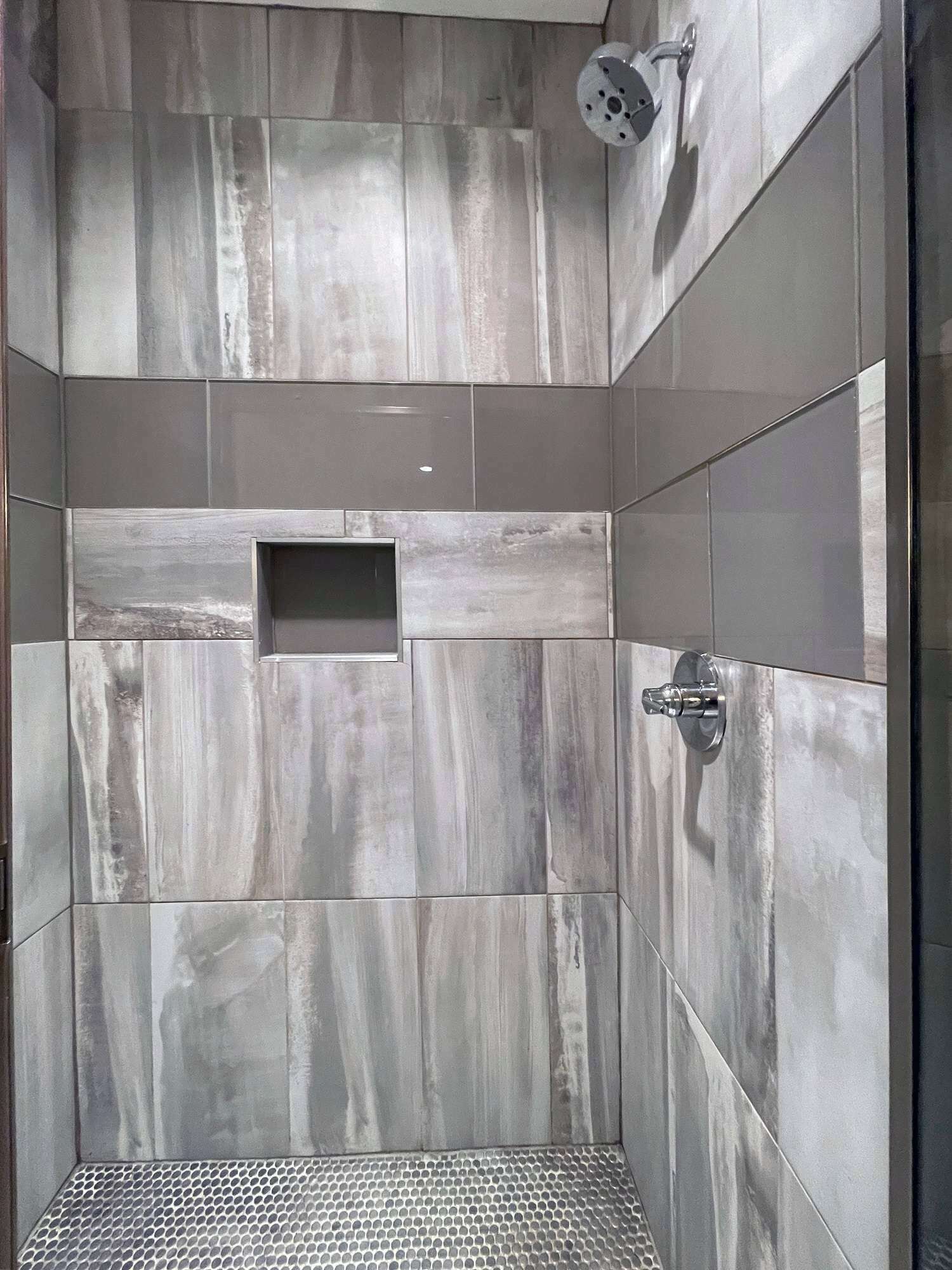 A shower with a rectangular niche, a showerhead, and a metal shower tray.