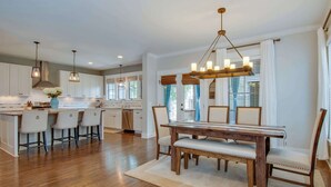 A spacious kitchen with a wooden dining table, bar stools, and pendant lighting. - Private Backyard | Near Bicentennial Park (Nashville)