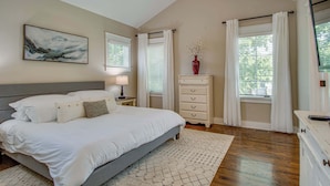 A bedroom with a bed, a nightstand, a dresser, a window with curtains, a ceiling fan, and a painting on the wall. - Private Backyard | Near Bicentennial Park (Nashville)