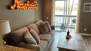 Un salon avec un canapé, une table basse et un panneau lumineux sur lequel on peut lire le mot « Nashville ».