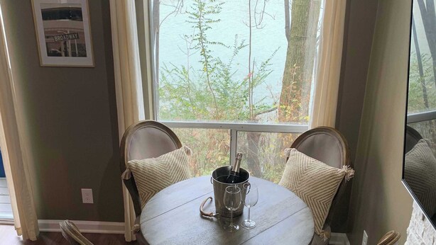 Un coin repas avec une table ronde, quatre chaises, une bouteille de champagne et deux verres à vin.