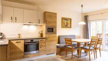 Una cocina moderna con armarios de madera, horno empotrado y comedor con mesa y sillas.