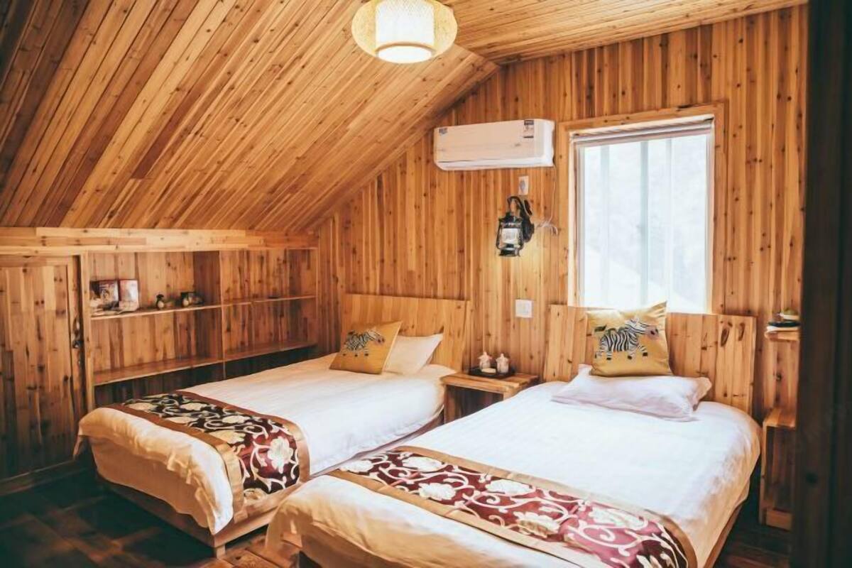 A wooden room with two beds, a window, and an air conditioning unit.