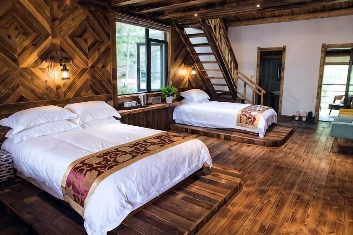A wooden room with two beds, a staircase, and a window.