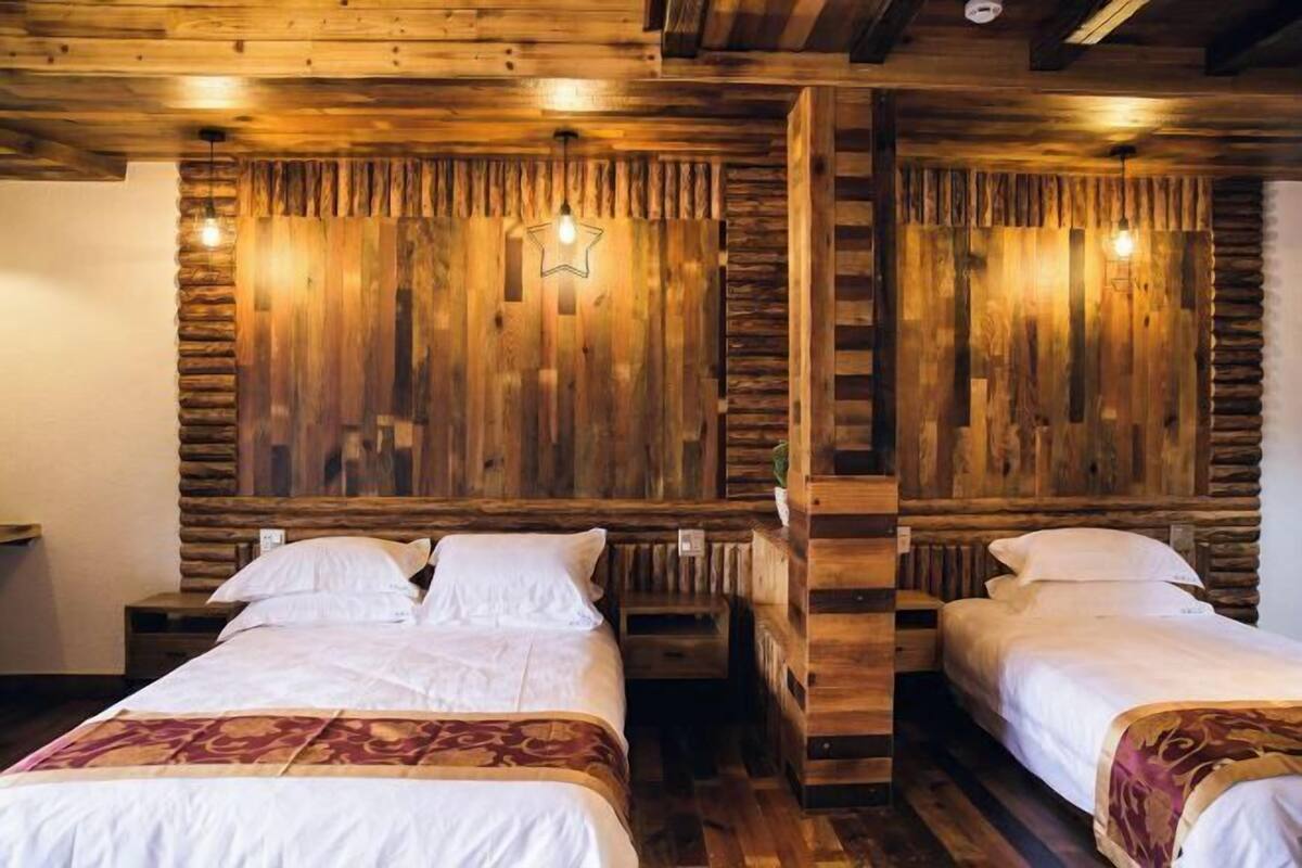 A room with two beds, wooden walls, and a star-shaped light fixture.