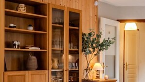 Un meuble en bois doté de portes en verre, contenant des ustensiles de cuisine et des objets décoratifs.