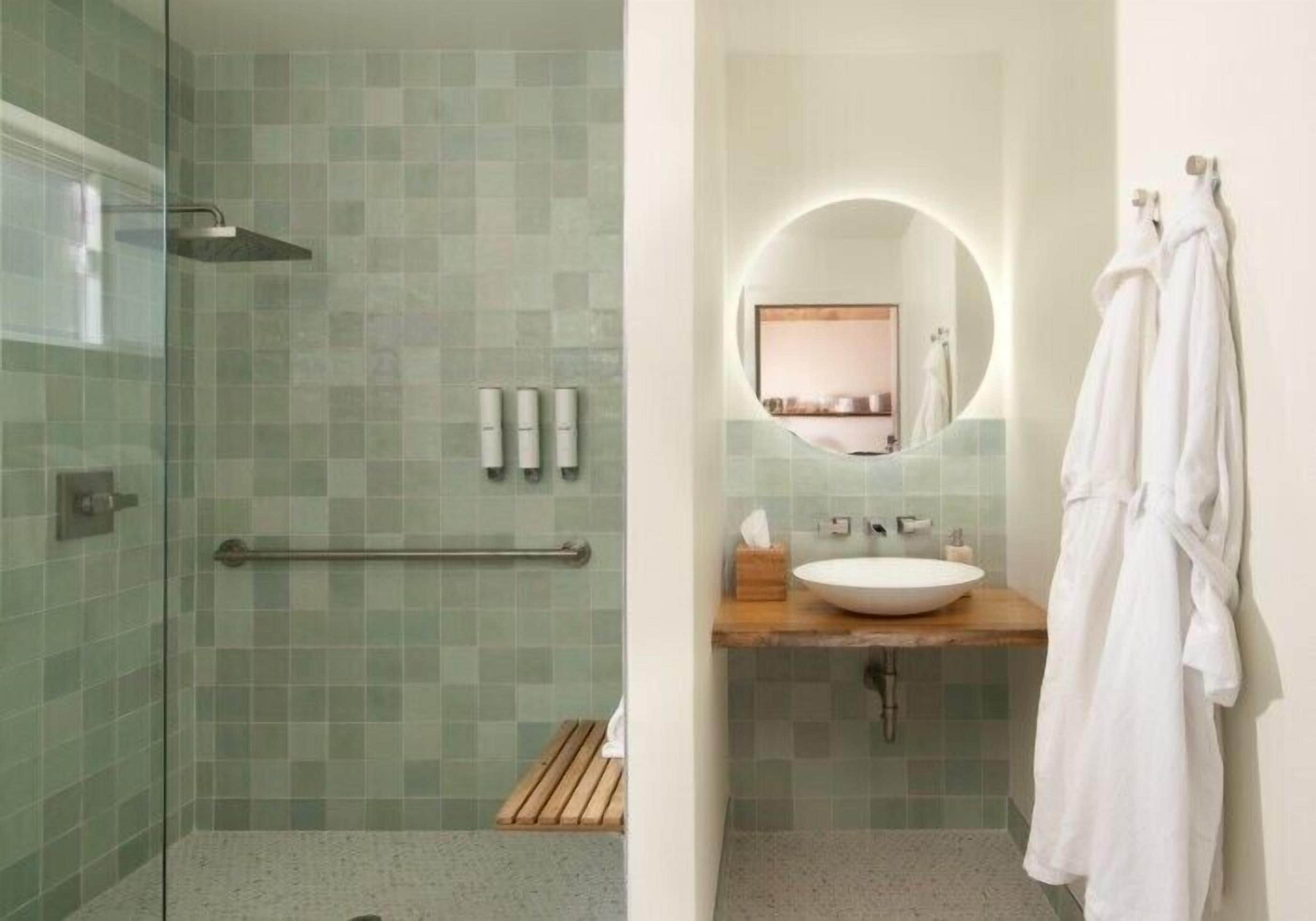 Un baño moderno con cabina de ducha de vidrio, tocador de madera y un perchero para toallas.
