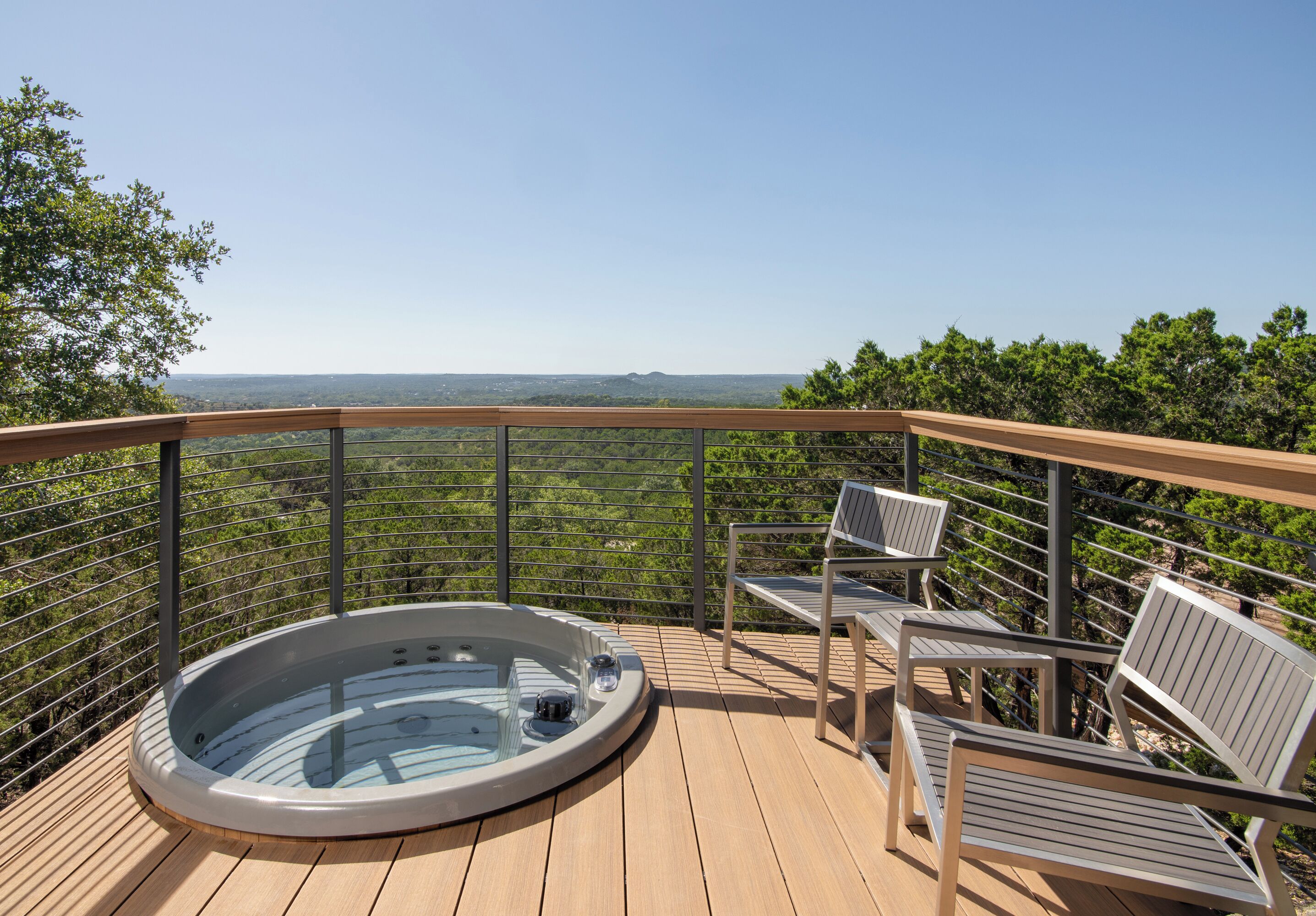 A hot tub on a wooden deck with a view of a forested landscape.