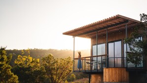 Une maison moderne dotée d’un balcon, de grandes fenêtres et d’une façade en bois.