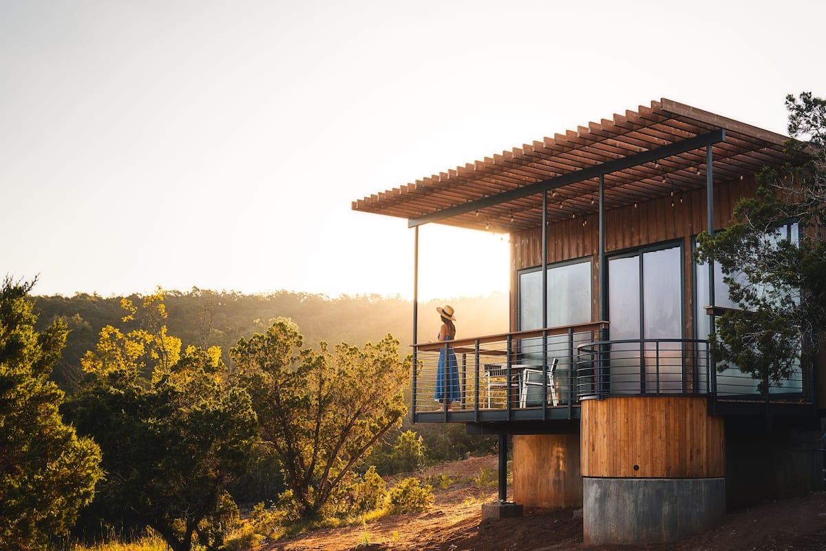A modern house with a balcony, large windows, and a wooden exterior.