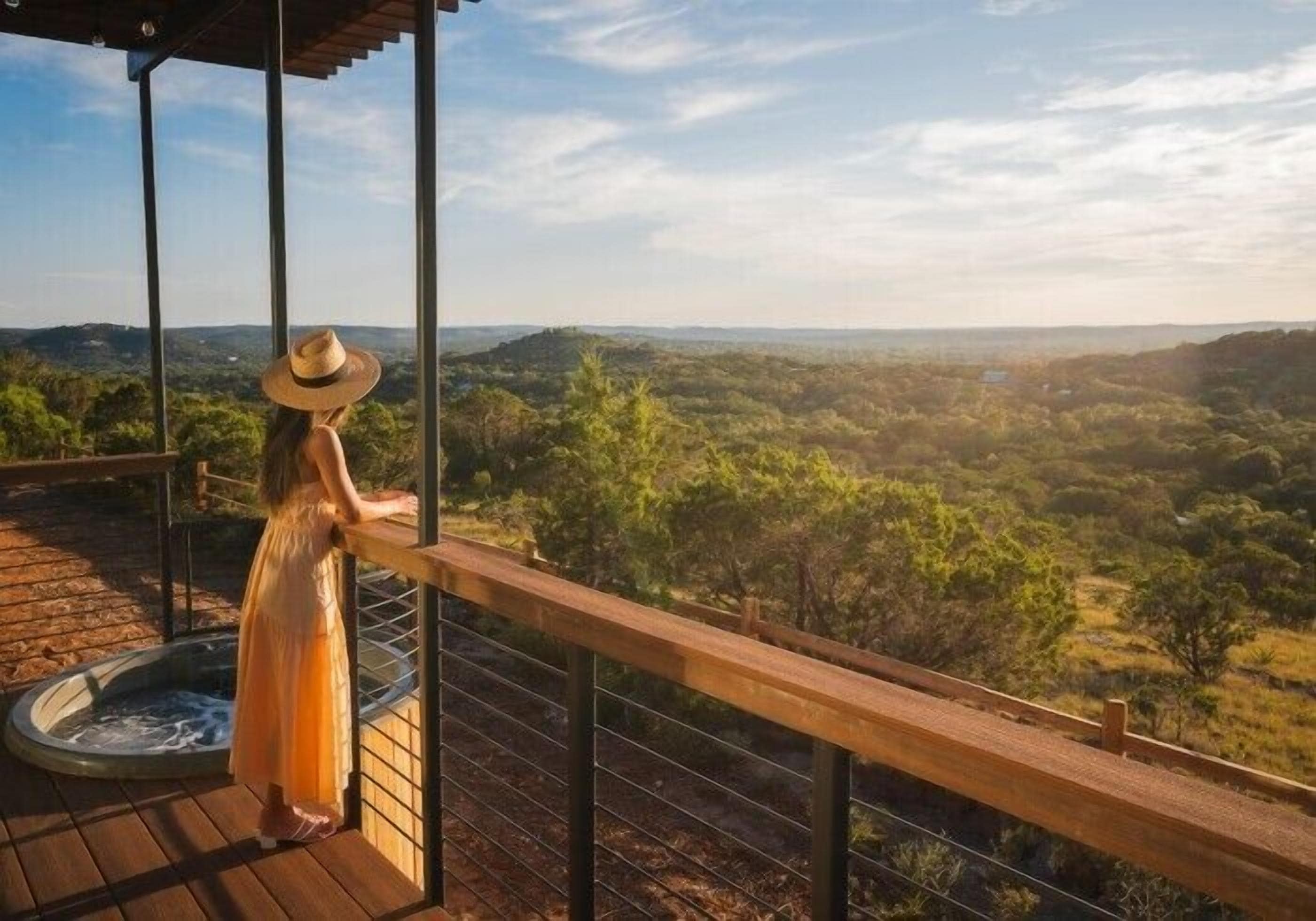 Una persona está de pie sobre una terraza de madera con vistas a un paisaje exuberante.