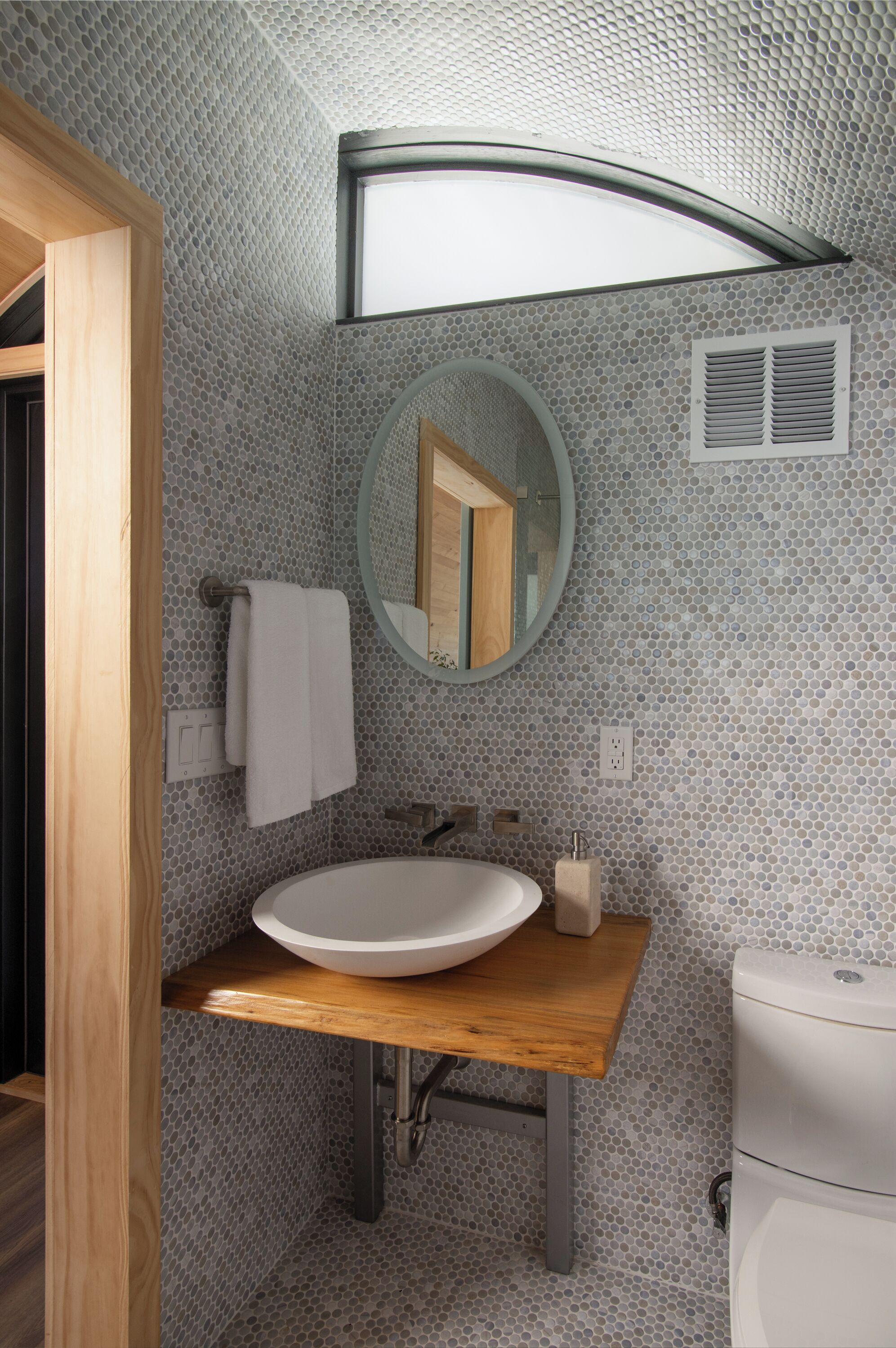 Une salle de bain avec un meuble-lavabo en bois, un miroir rond et un lavabo blanc.