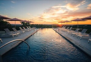 Una piscina al aire libre, sombrillas, sillones reclinables de piscina