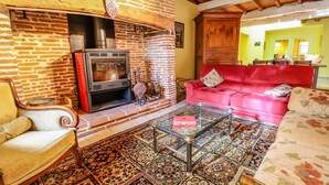 Una sala de estar acogedora con chimenea de ladrillo, un sofá rojo y una mesa de centro de vidrio.