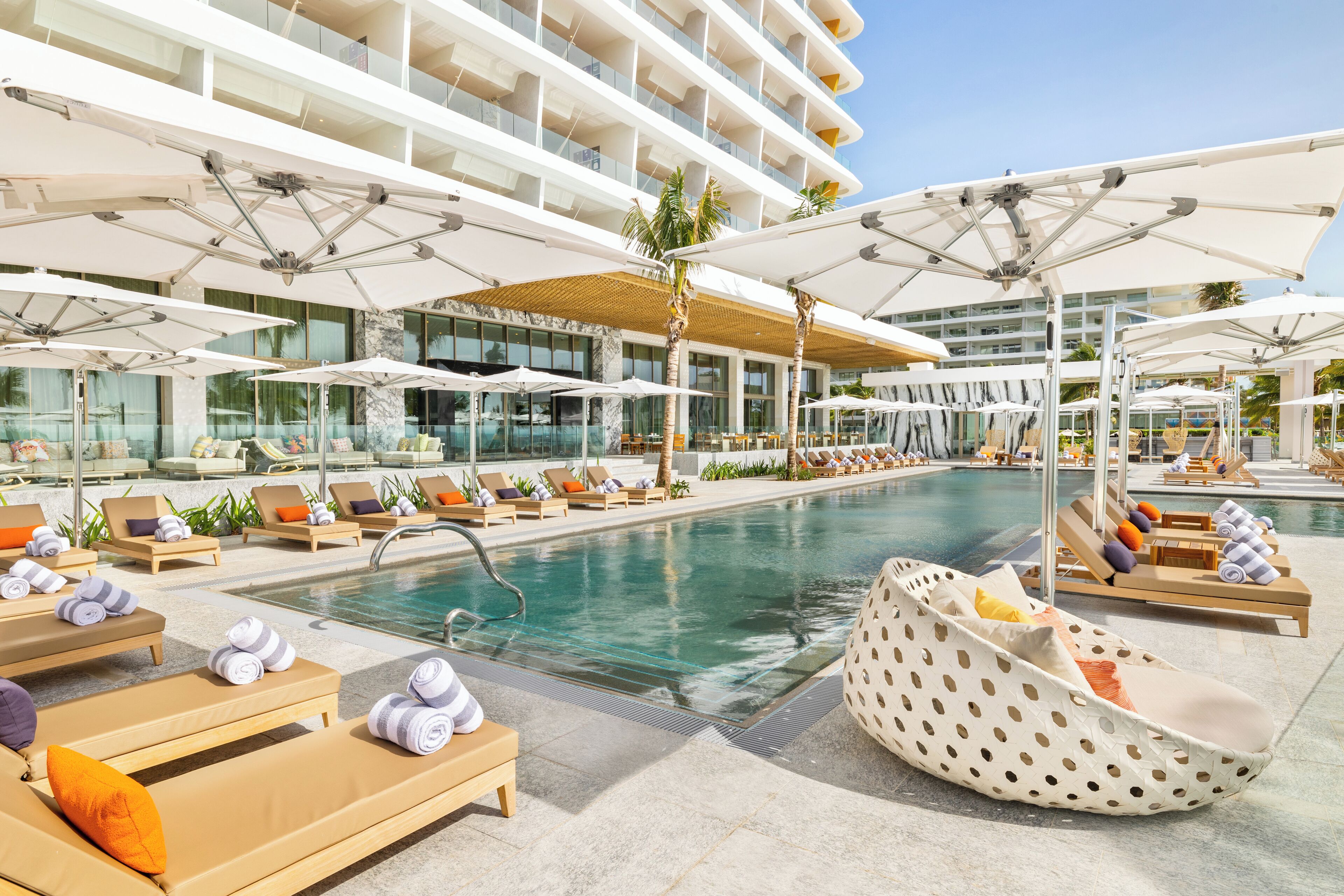 A poolside area with sun loungers, umbrellas, and a pool.