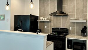 Una cocina moderna con estufa negra, armarios blancos y microondas integrado.