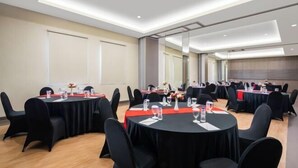 Un salón de conferencias con mesas redondas, sillas negras y manteles rojos.
