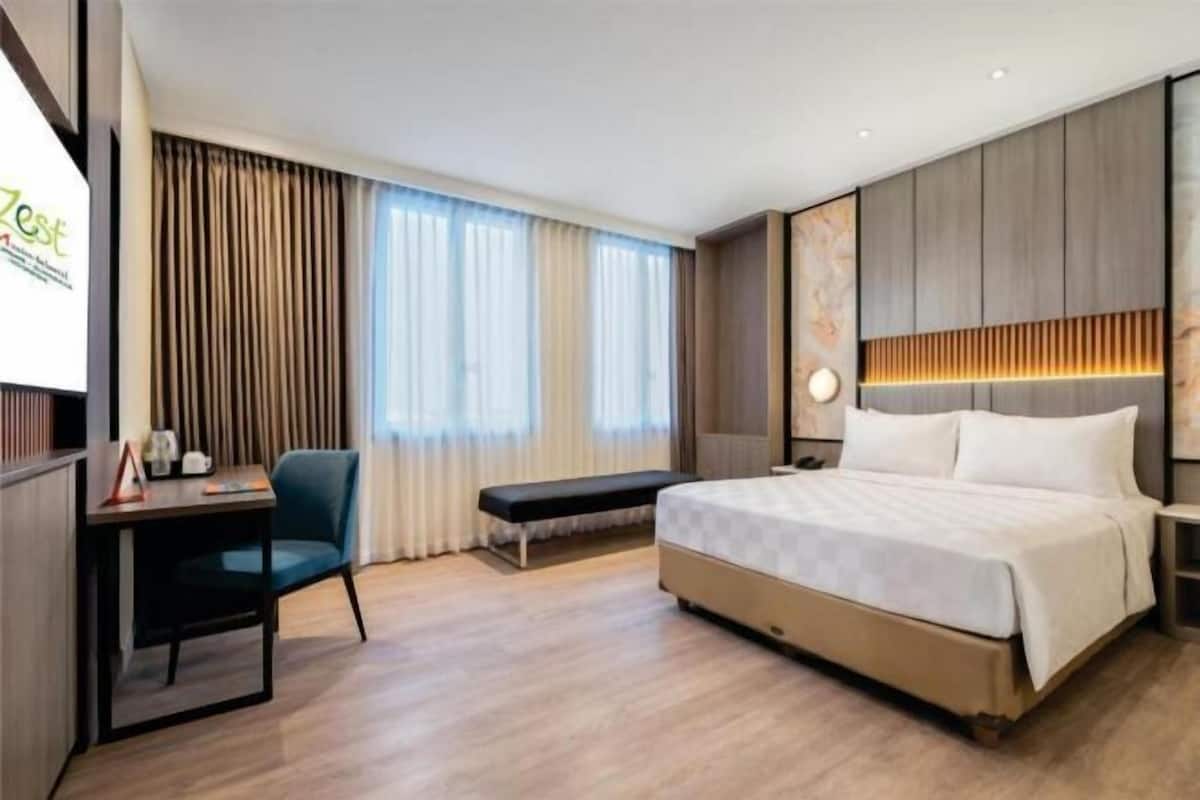 Moderni hotellihuone, jossa on sänky, työpöytä ja tuoli.
