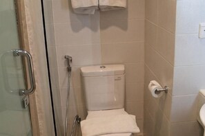 A bathroom with a toilet, a glass shower enclosure, and a towel rack. - Swiss-Belexpress Jemursari (Tenggilis Mejoyo)
