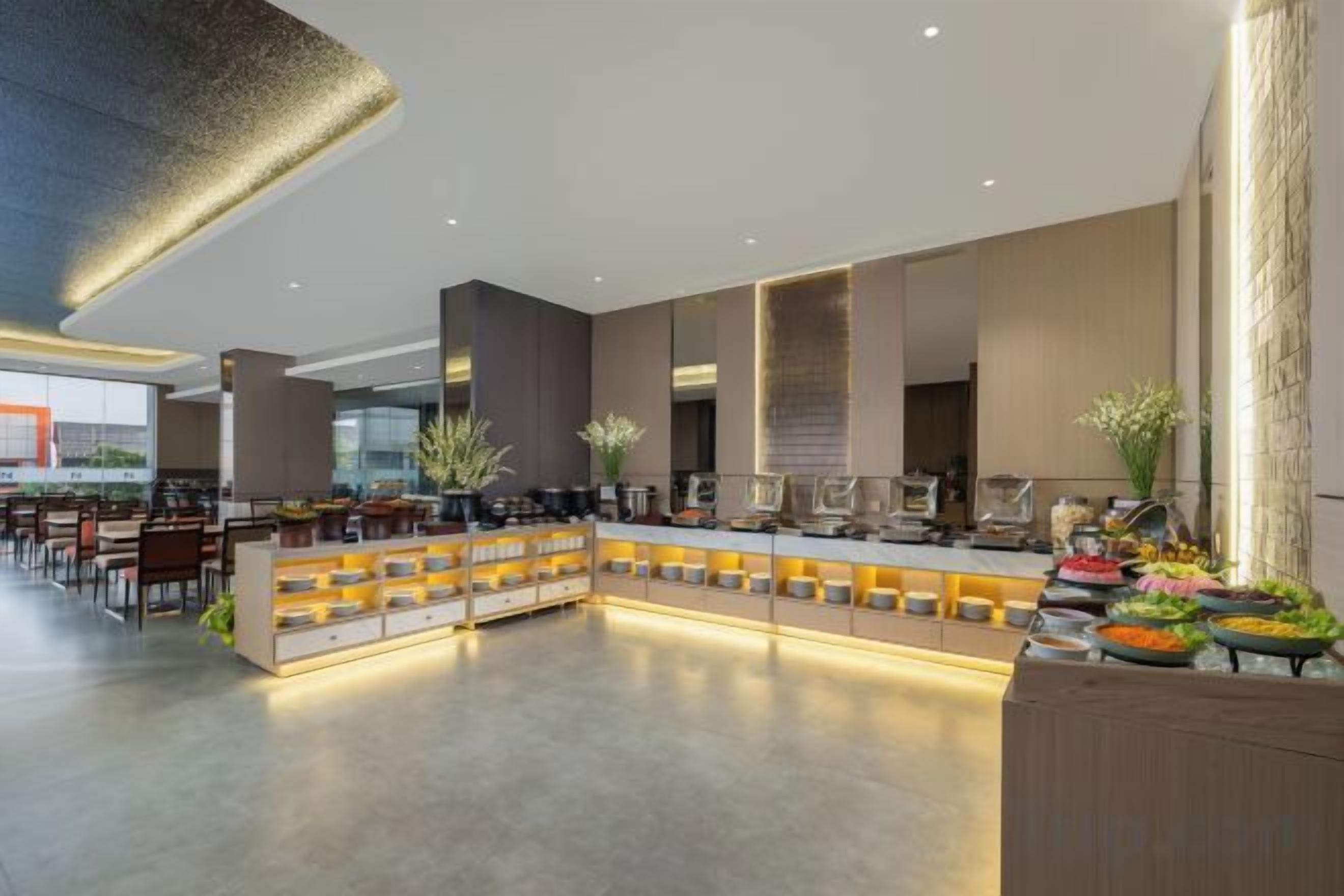 Una moderna hall d'albergo con reception centrale, area lounge e buffet.