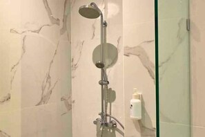 Eine Dusche mit Handbrause und Bedieneinheit an der Wand.