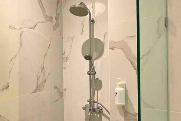 A shower with a handheld showerhead and a wall-mounted control panel.