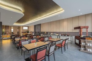 Een modern restaurant met meerdere eettafels en stoelen, een keuken en een toonbank met diverse etenswaren.