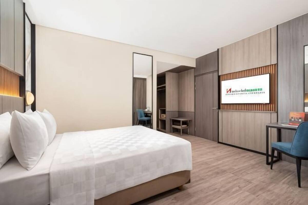 Hotellihuone, jossa on sänky, työpöytä, tuoli ja vaatekaappi.