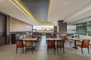 A spacious restaurant with high ceilings and a modern design, featuring multiple dining tables and chairs. - Swiss-Belexpress Jemursari (Tenggilis Mejoyo)