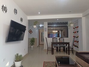 Un soggiorno moderno con una TV a schermo piatto, un'area pranzo con tavolo e sedie, e un divano.