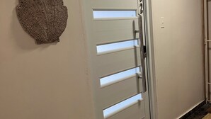 A modern entrance with a sliding door, a welcome mat, and a textured wall decoration. - Seaside getaway in Isla Verde beach for 4 guest. Book now! (Carolina)
