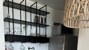 A modern kitchen with wooden cabinets, a stainless steel refrigerator, and a black metal shelving unit above the sink. - Seaside getaway in Isla Verde beach for 4 guest. Book now! (Carolina)