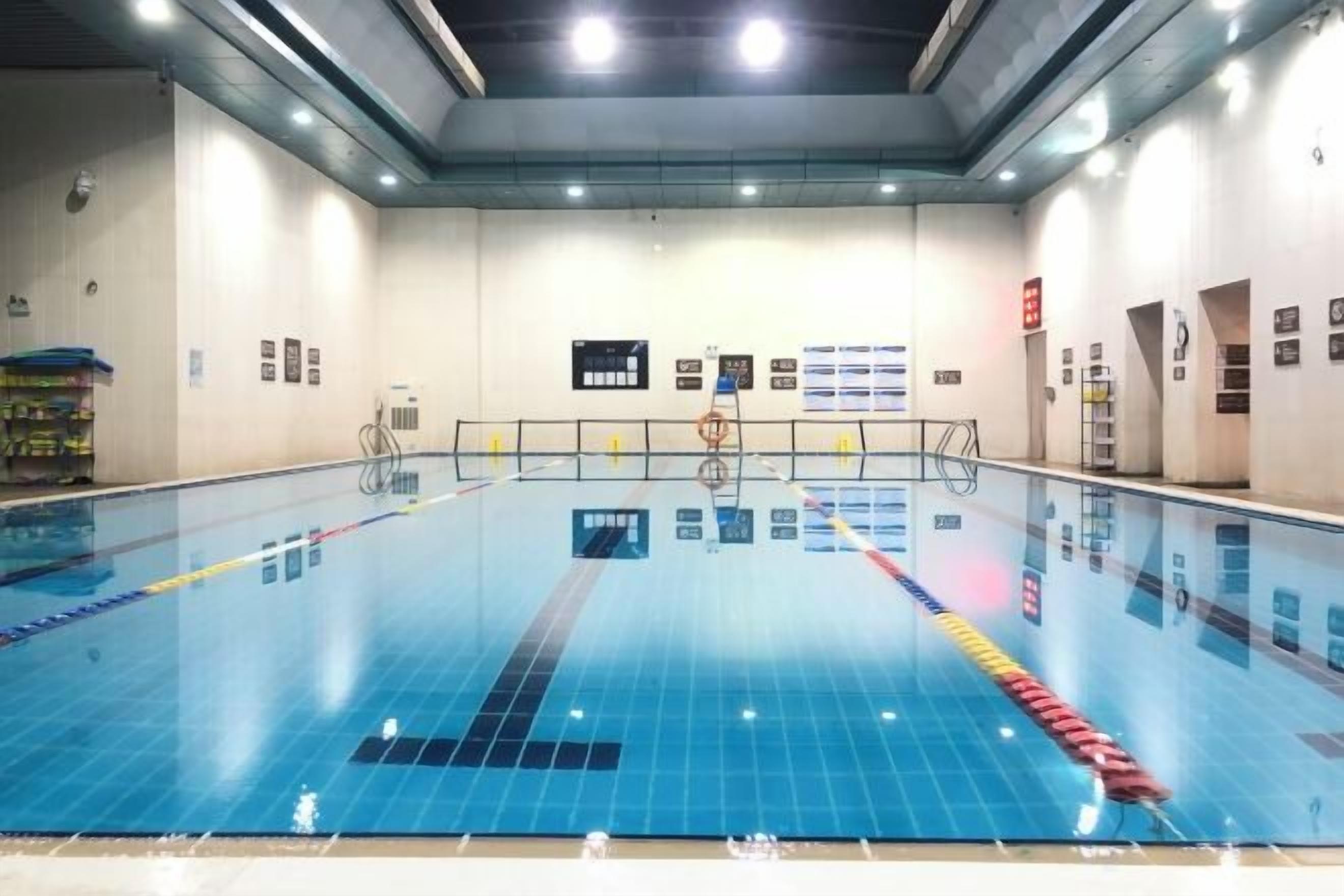An indoor swimming pool with lane dividers, a starting block, and a lifeguard chair.