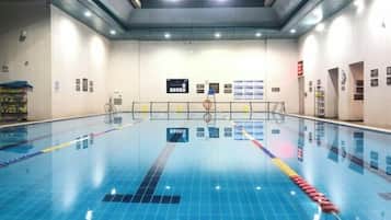 An indoor swimming pool with lane dividers, a starting block, and a lifeguard chair.