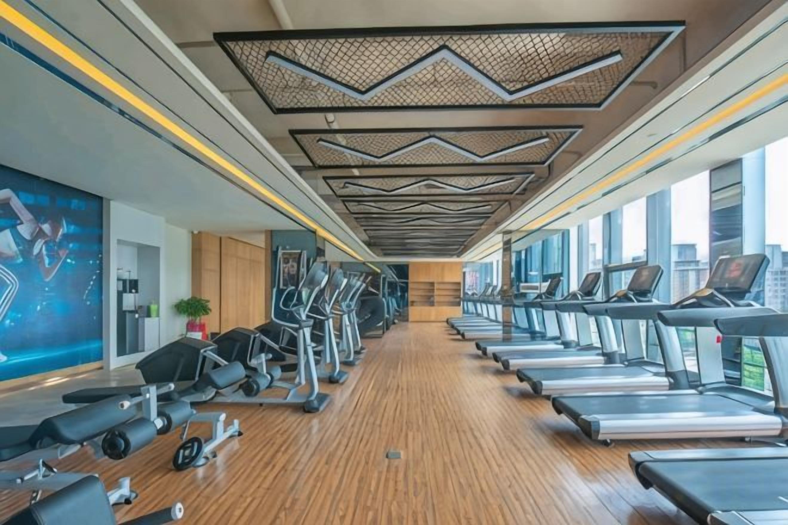 Une salle de sport équipée de tapis de course, de vélos elliptiques et d'appareils de musculation.