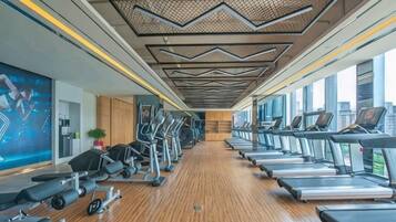 Une salle de sport équipée de tapis de course, de vélos elliptiques et d'appareils de musculation.