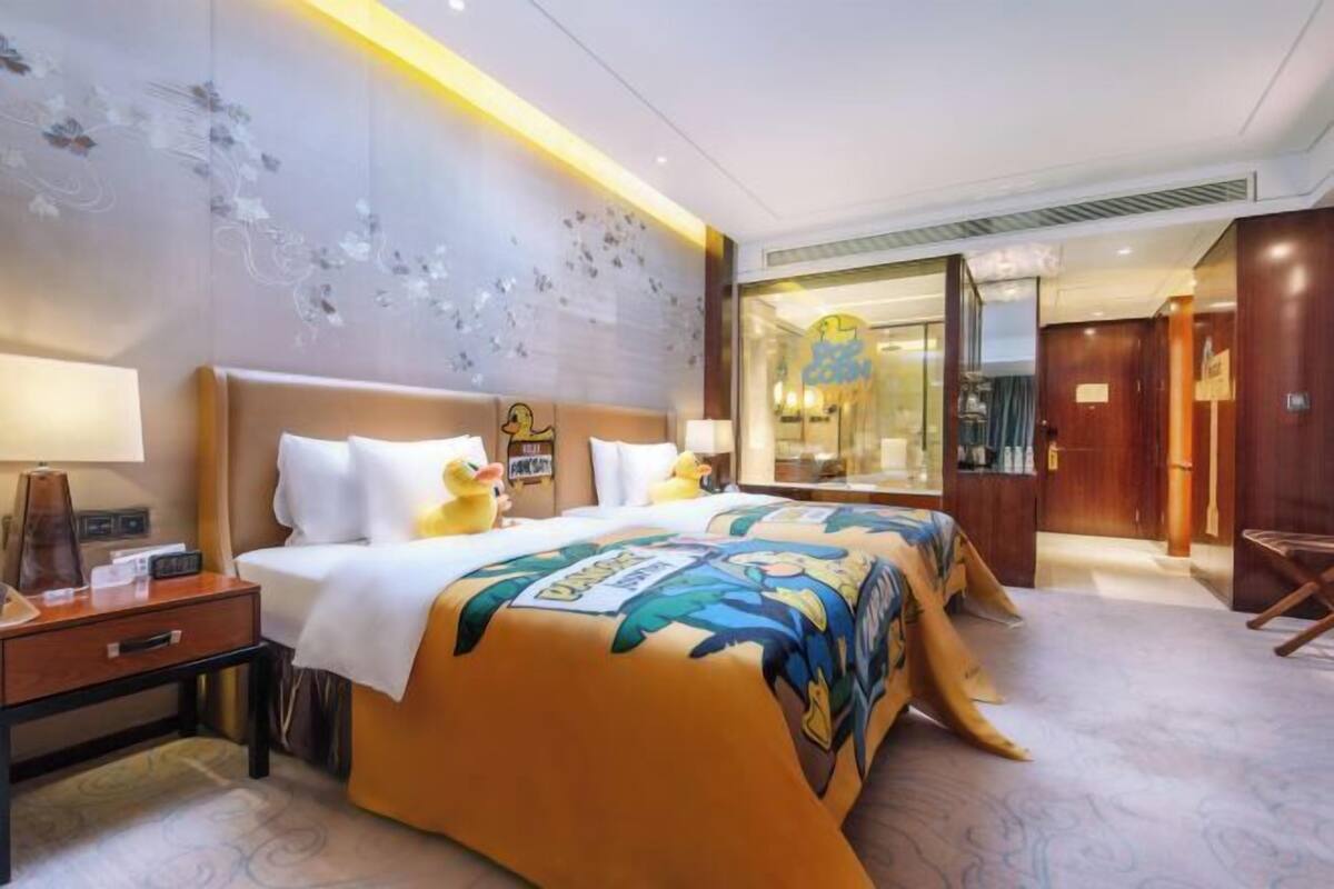 A hotel room with a bed, bedside table, and a large window.