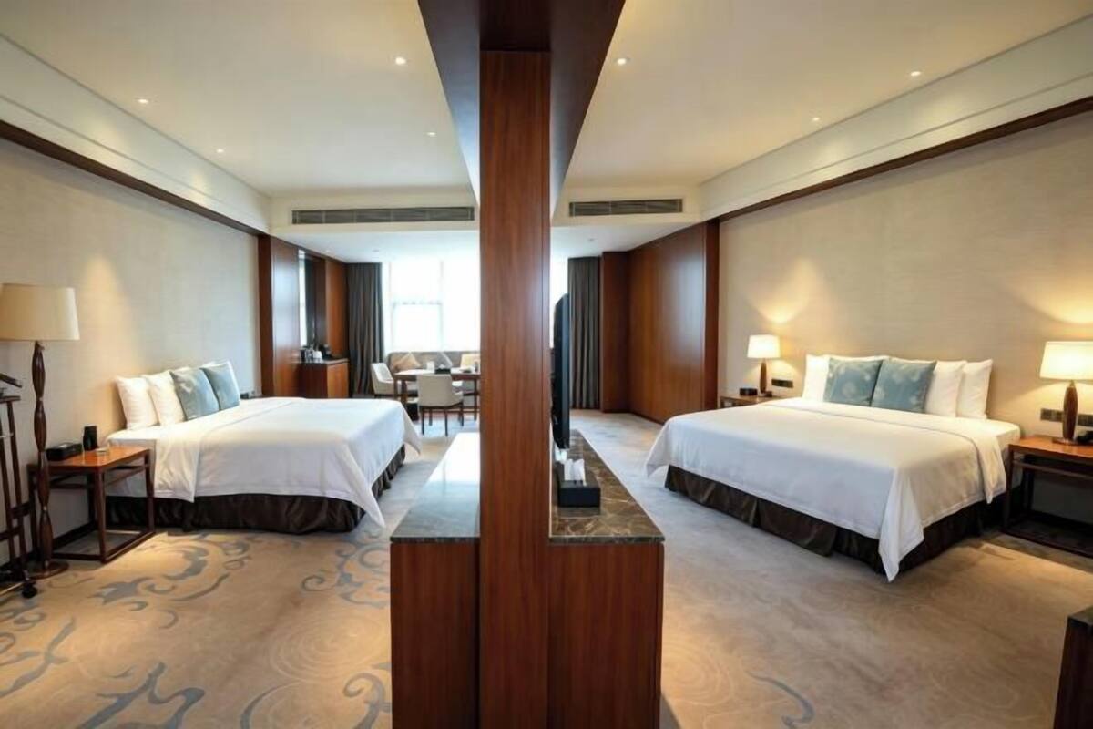 A hotel room with two beds, a desk, and a TV.