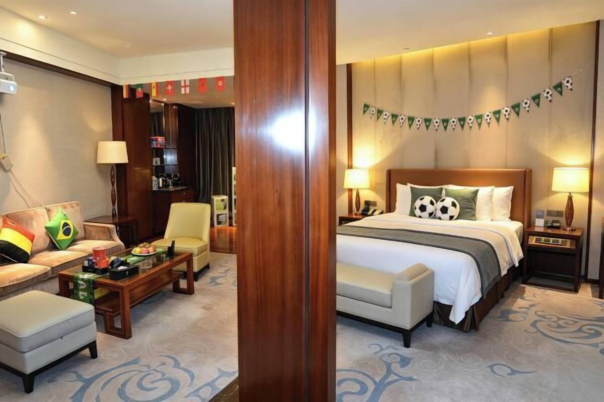 A hotel room with a bed, a sofa, a coffee table, and a desk.