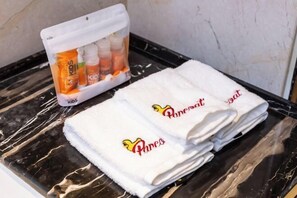 A bathroom with a marble countertop, a set of folded towels with a logo, and a container of children's vitamins.